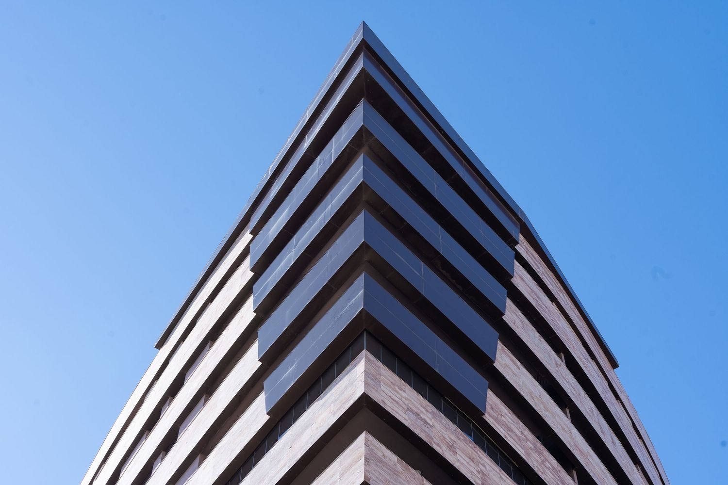 Modern architectural building photographed at dusk in Málaga, with soft blue hour tones and warm interior lighting defining structure and at
