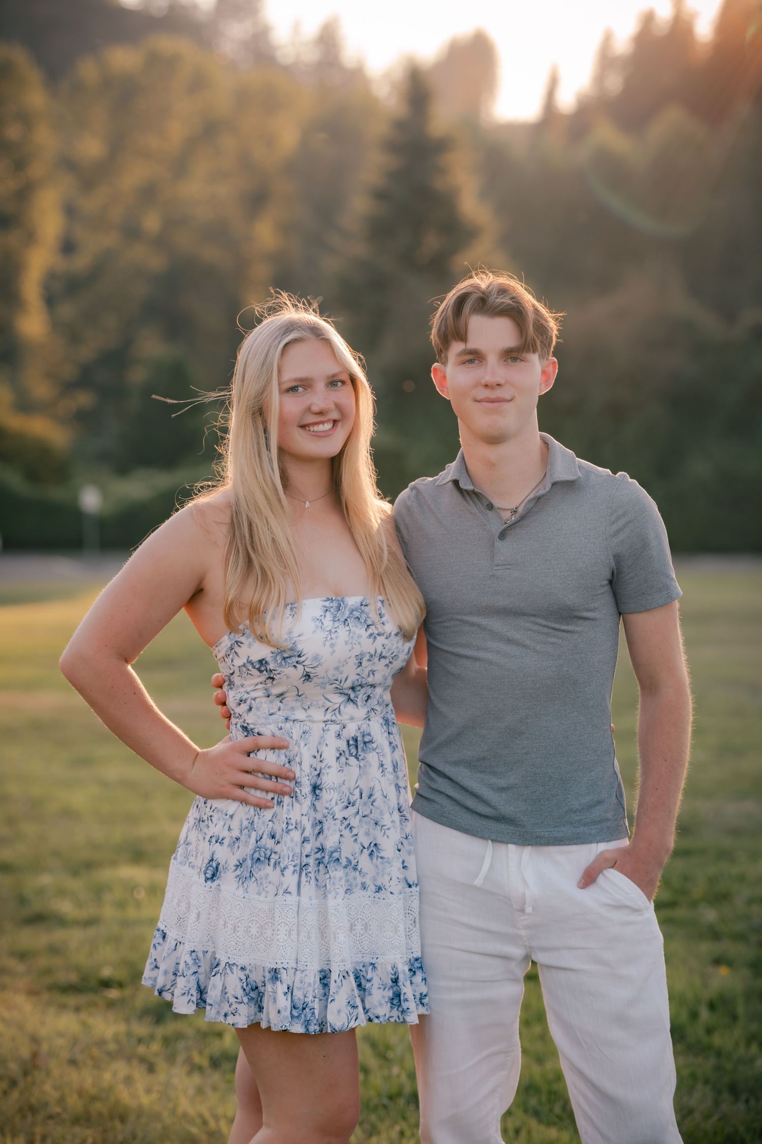 Couple posing together outdoors at sunset in coordinated blue and white outfits.