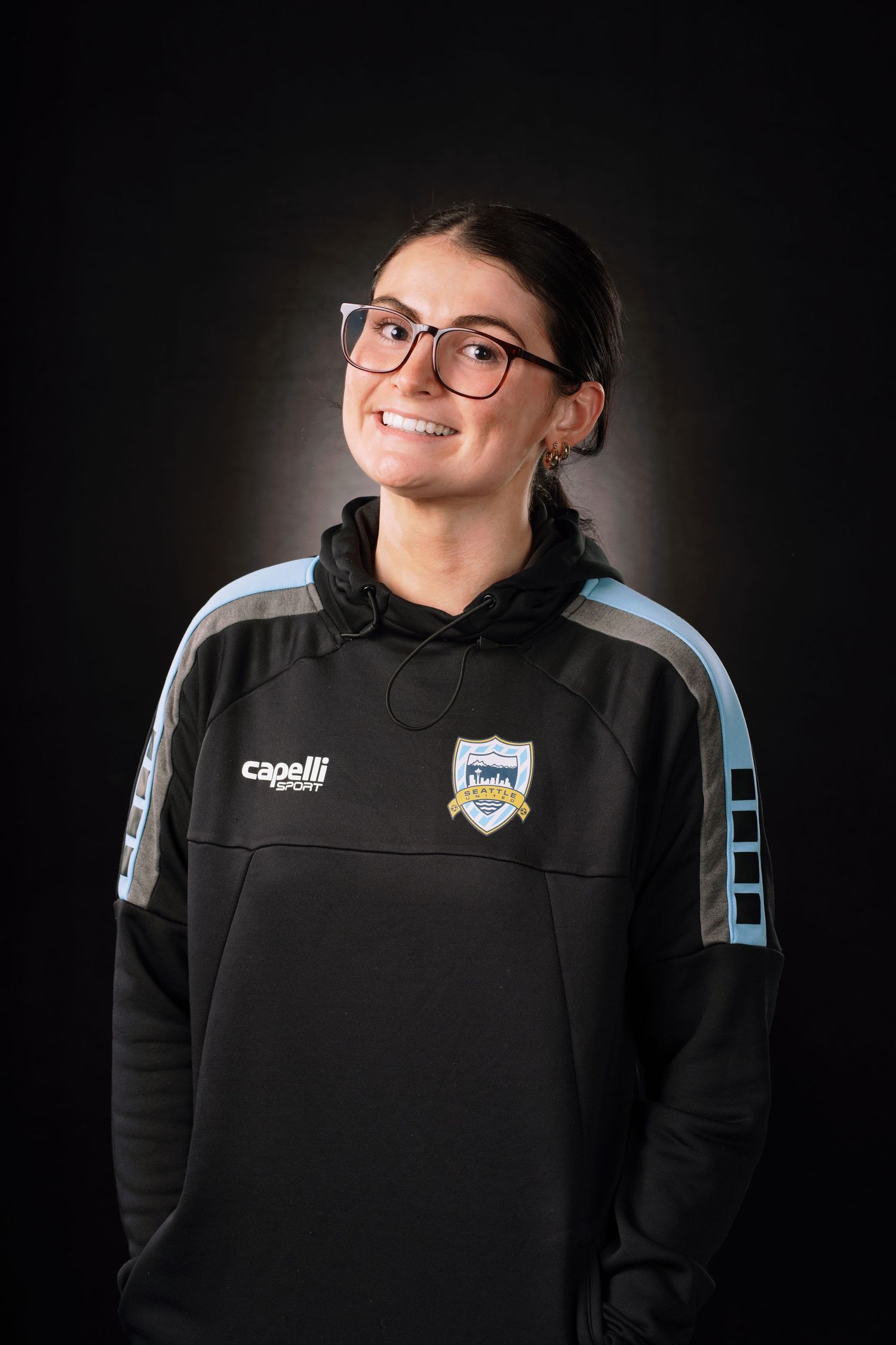 Athletic person in black Capelli Sport hoodie with team logo shown in multiple poses against dark background.