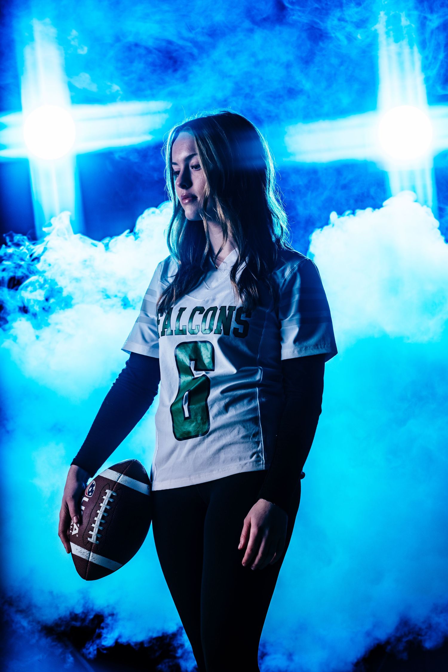 Athletic figure in Falcons jersey holding football poses against dramatic blue lighting and smoke effects.