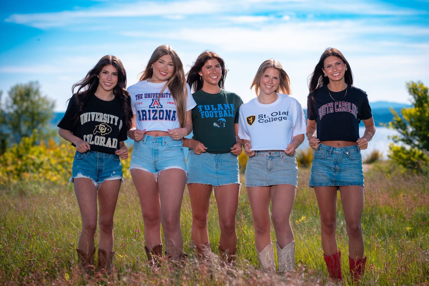 A group of friends in casual summer outfits standing together in a sunny wildflower field.