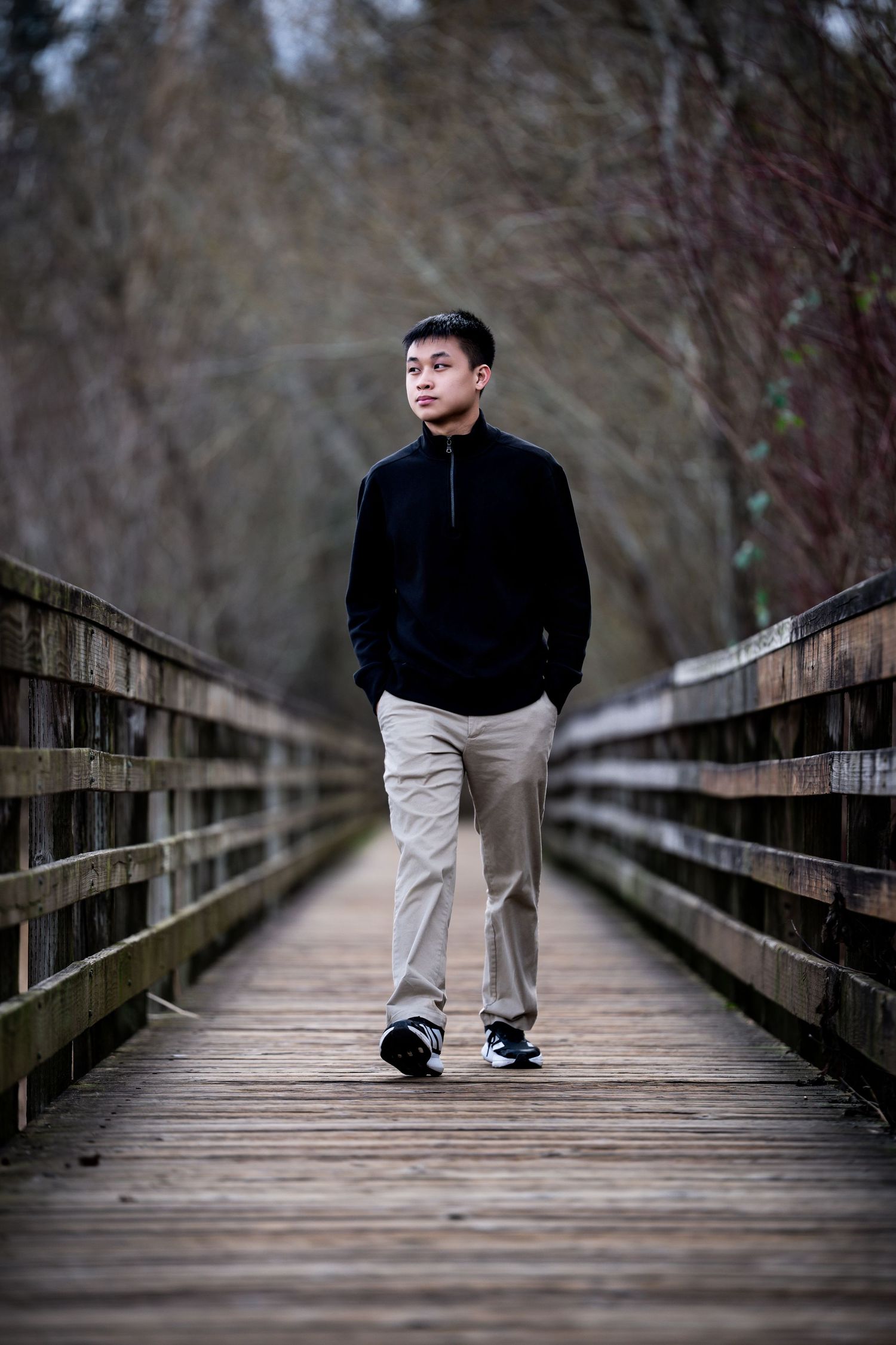 A series of four photos showing someone in black jacket and khaki pants standing on a wooden bridge walkway in nature.
