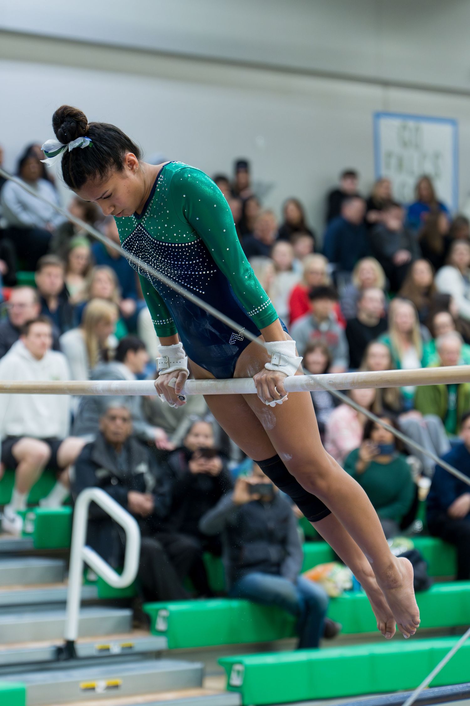 A gymnast performs a dynamic aerial routine on the uneven bars during a competitive event.