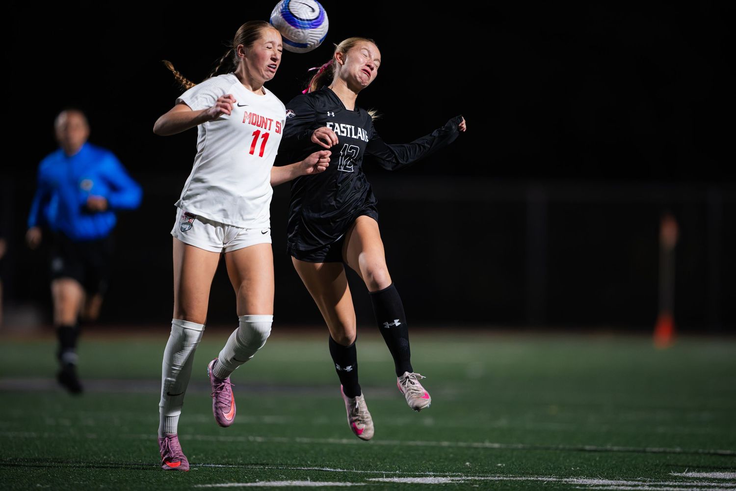 Soccer players compete for possession of the ball during an intense nighttime match on the field.