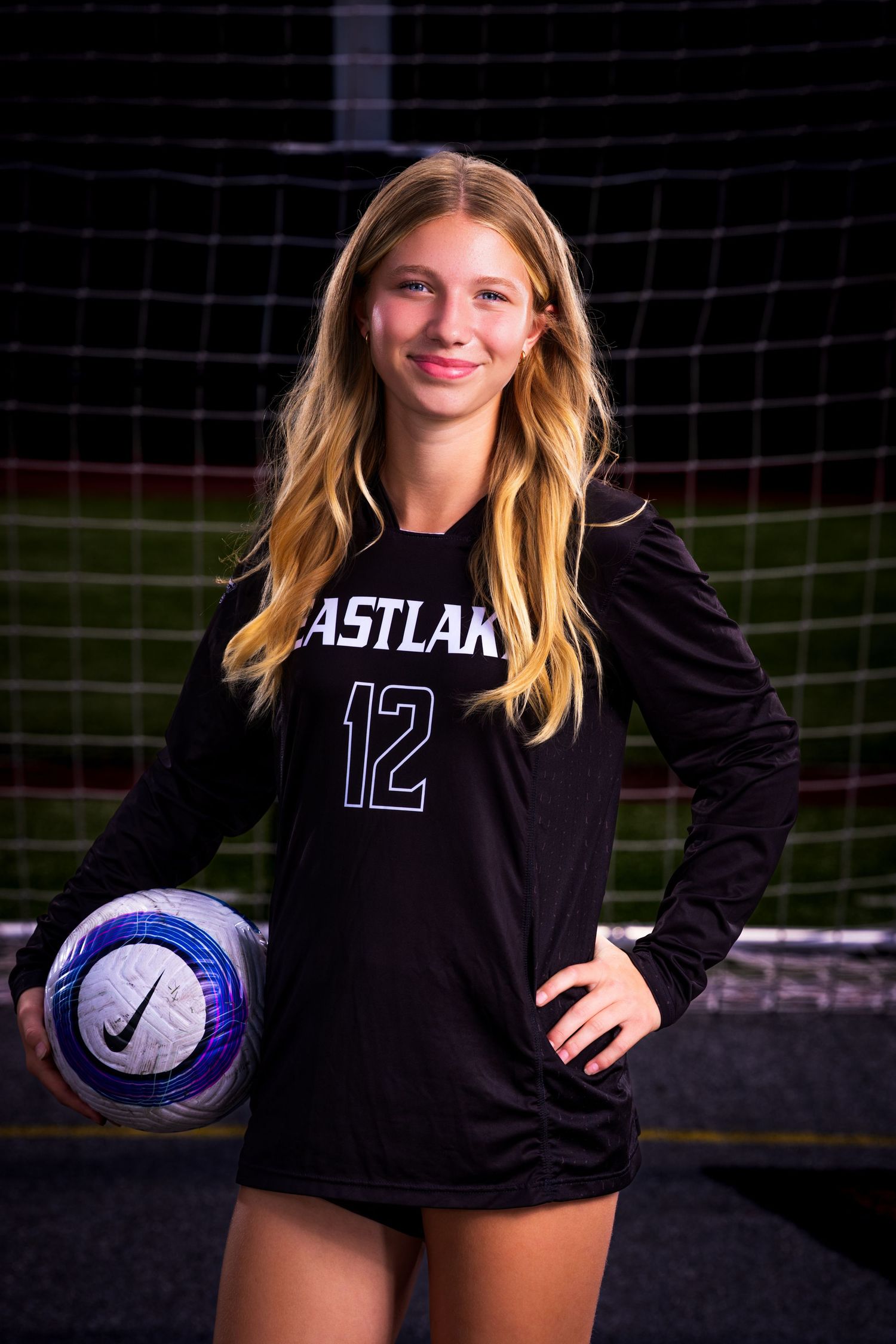 Soccer player in black Eastlake uniform poses with ball on field.