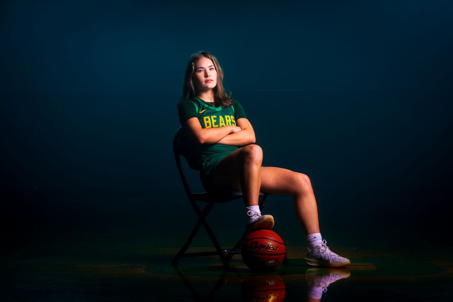 Athletic figure posing with basketball against deep blue studio backdrop.