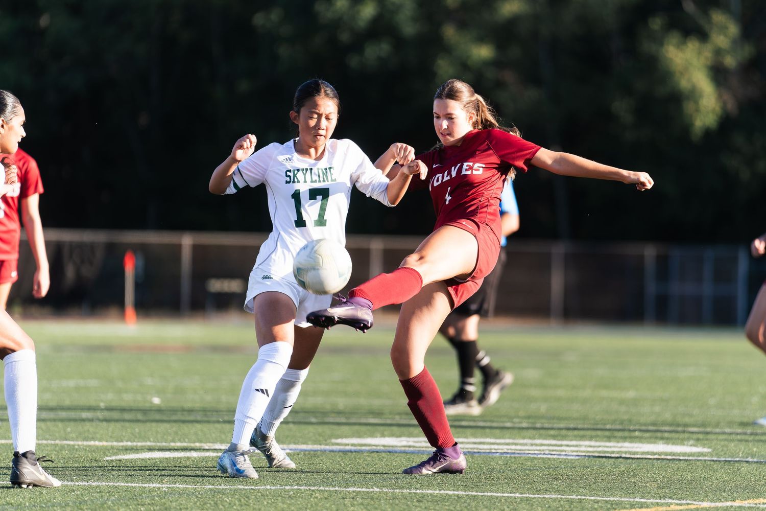 Soccer players compete for possession of the ball during an intense match on a sunny day.