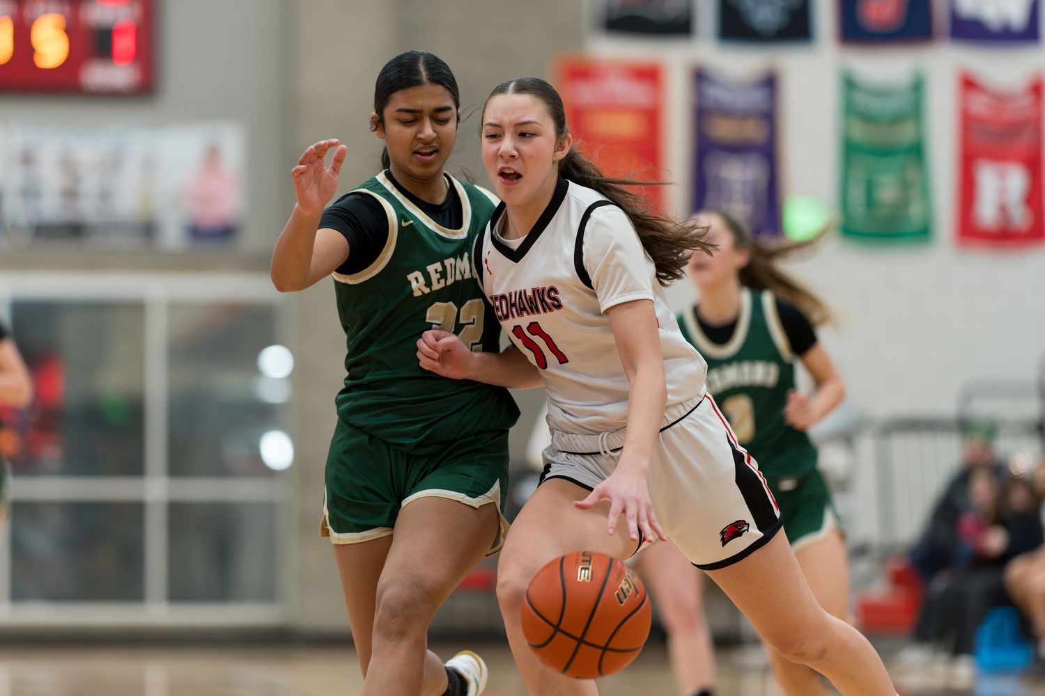 High school basketball players from opposing teams compete for possession during an intense game.