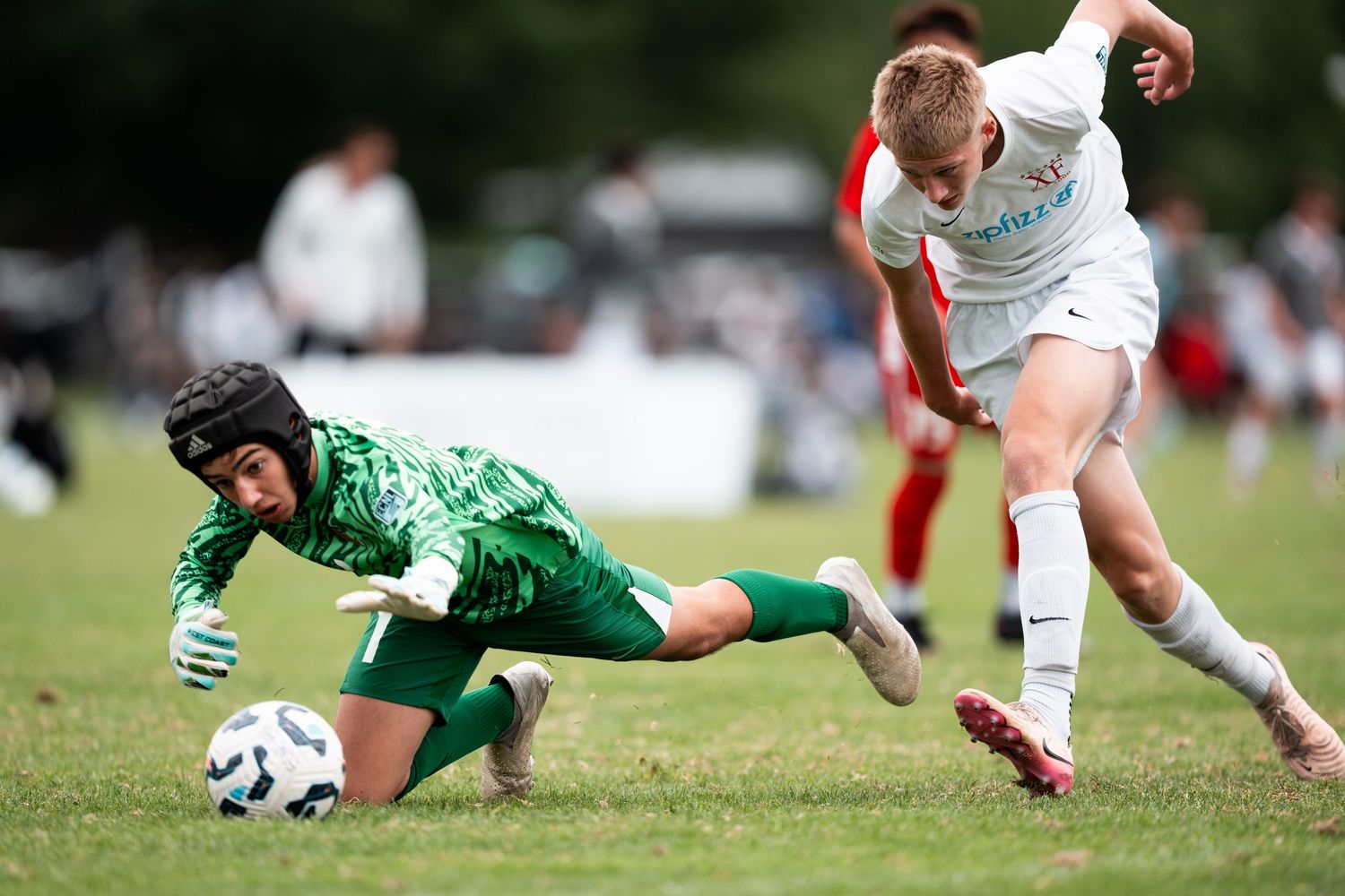 Rugby players dive and tackle during an intense match between teams in white and green uniforms.