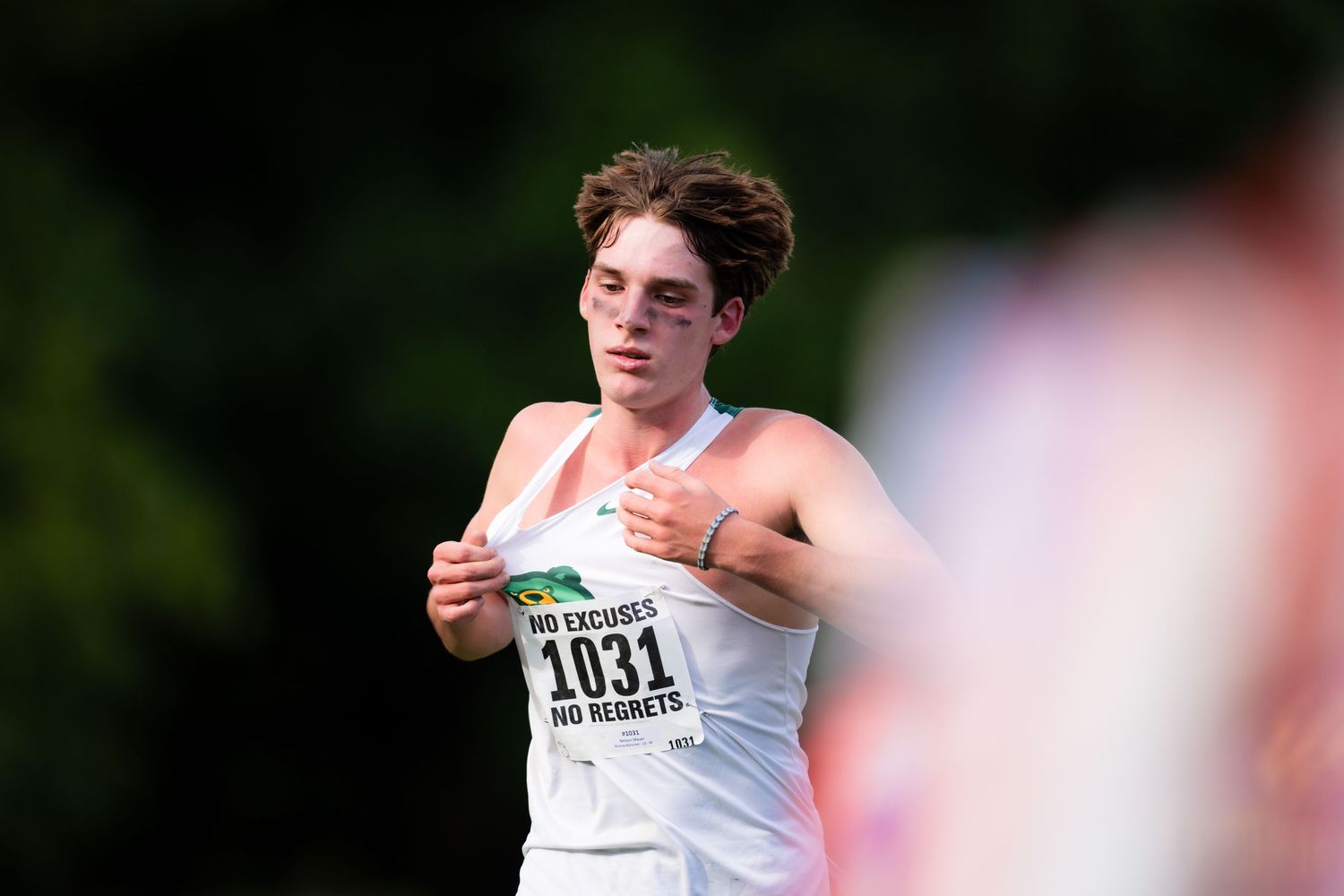 Track and field athlete in white jersey number 1031 competes in throwing event at outdoor competition.