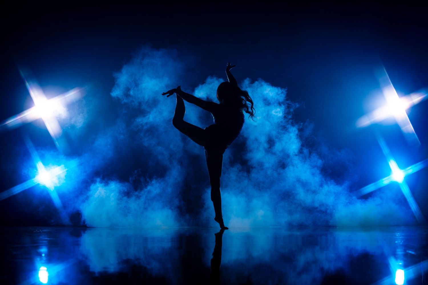 Artistic dance silhouettes with blue star lighting effects and fog.