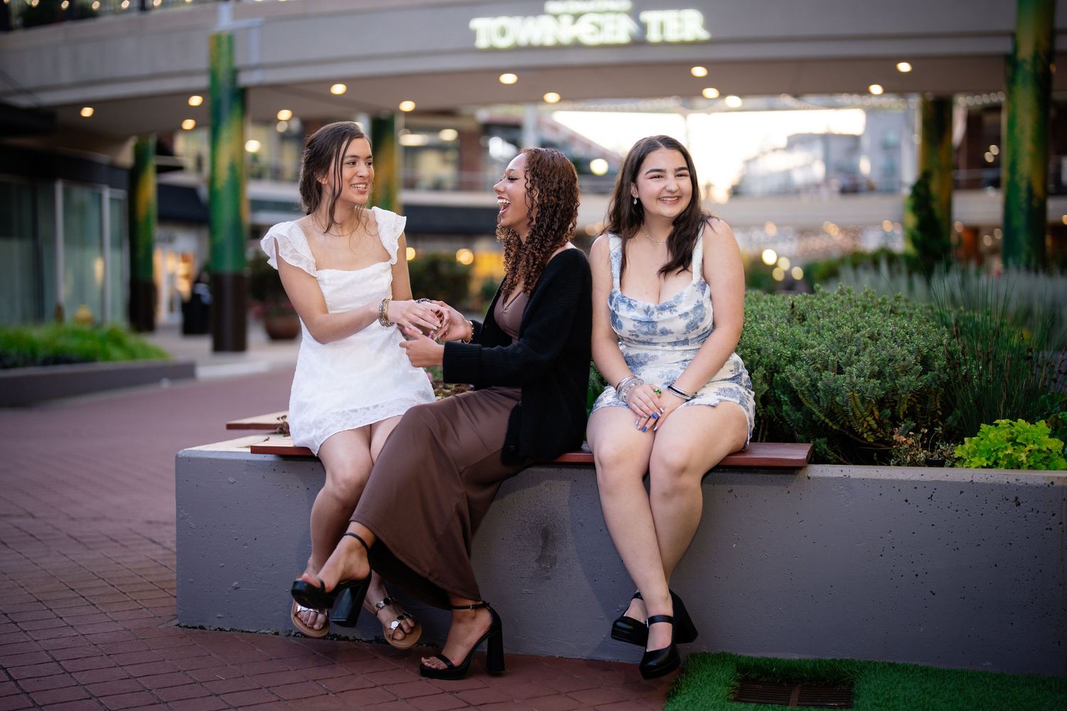 Group of people sitting and relaxing on outdoor benches near a shopping area.