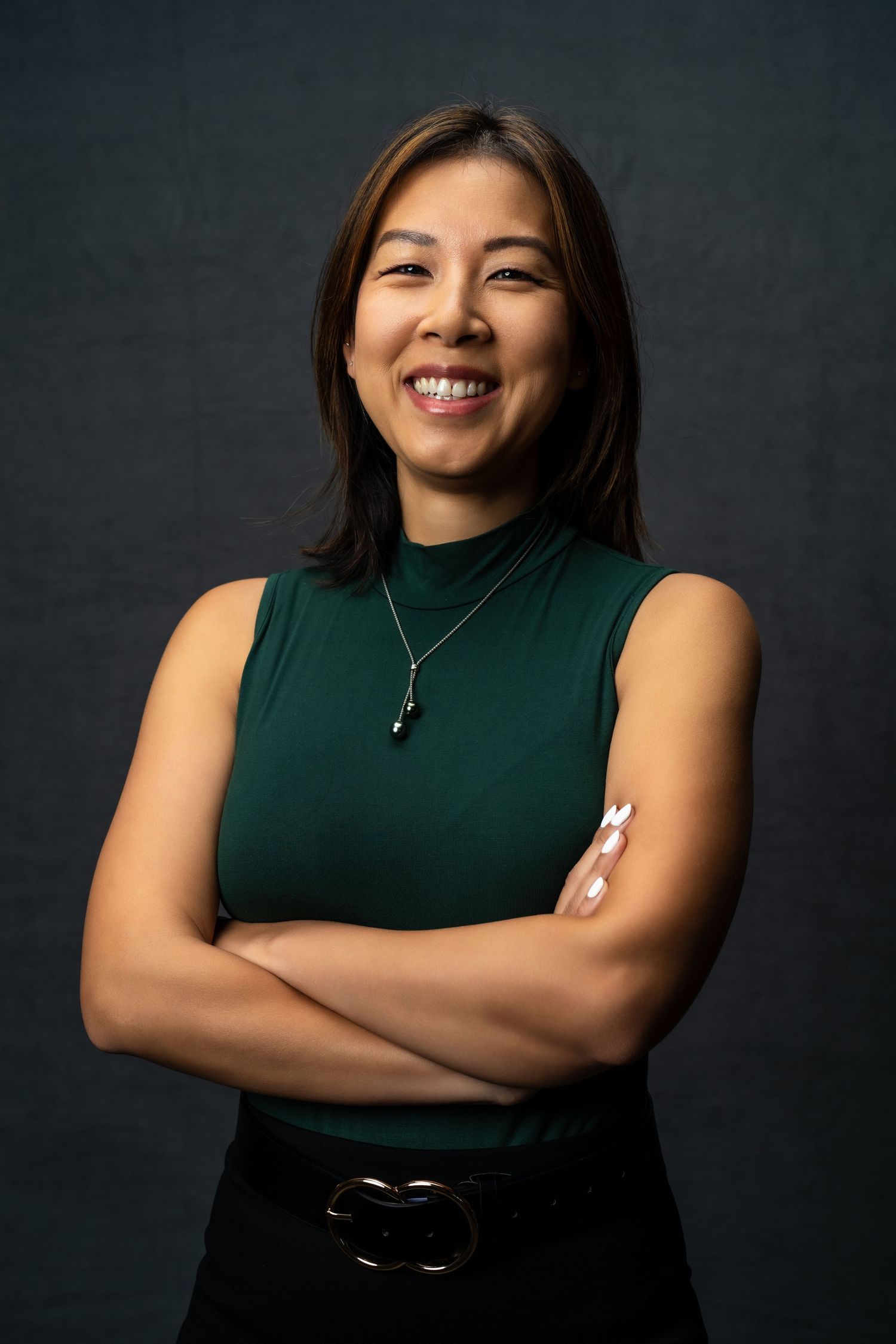 Professional headshot series of a woman in a dark sleeveless top against a moody background showing various expressions.