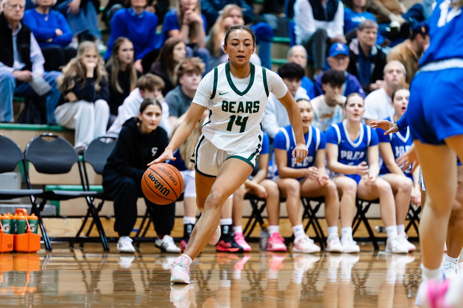 High school basketball players in blue and white uniforms compete during an intense game on the court.