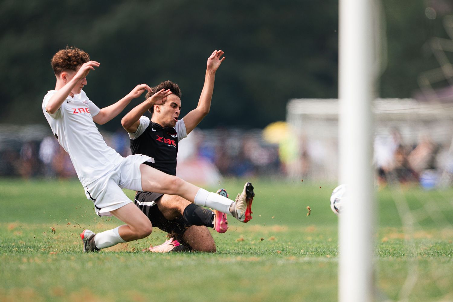 Two soccer players collide while competing for the ball during an intense match on a grass field.