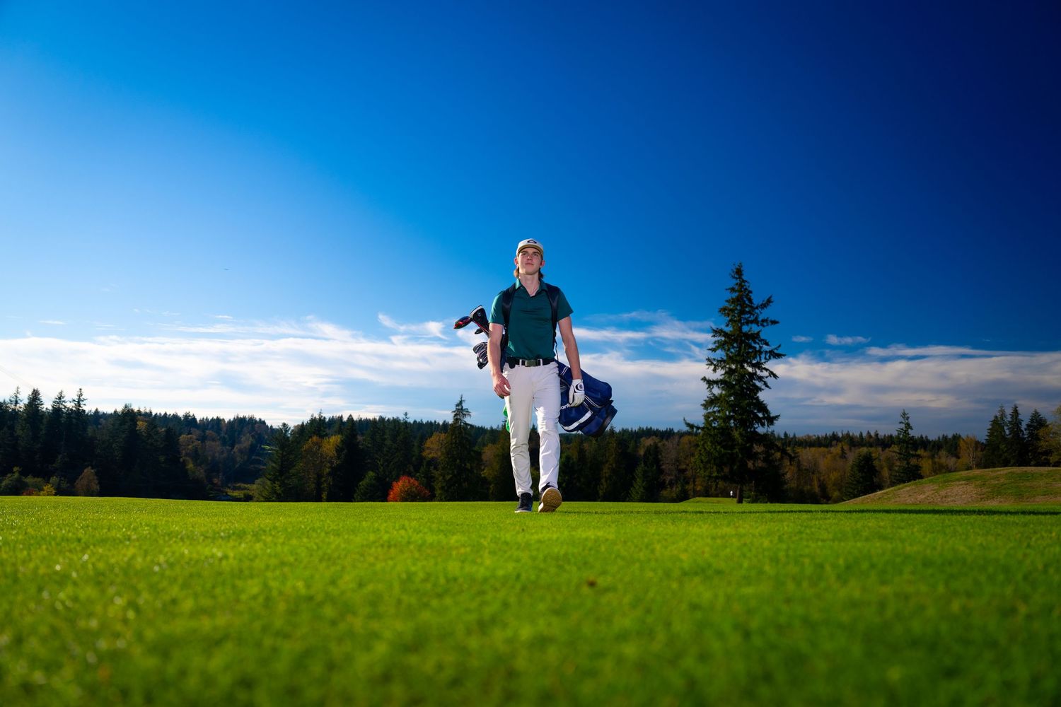 A person leaps joyfully in a green meadow against a bright blue sky and distant treeline.