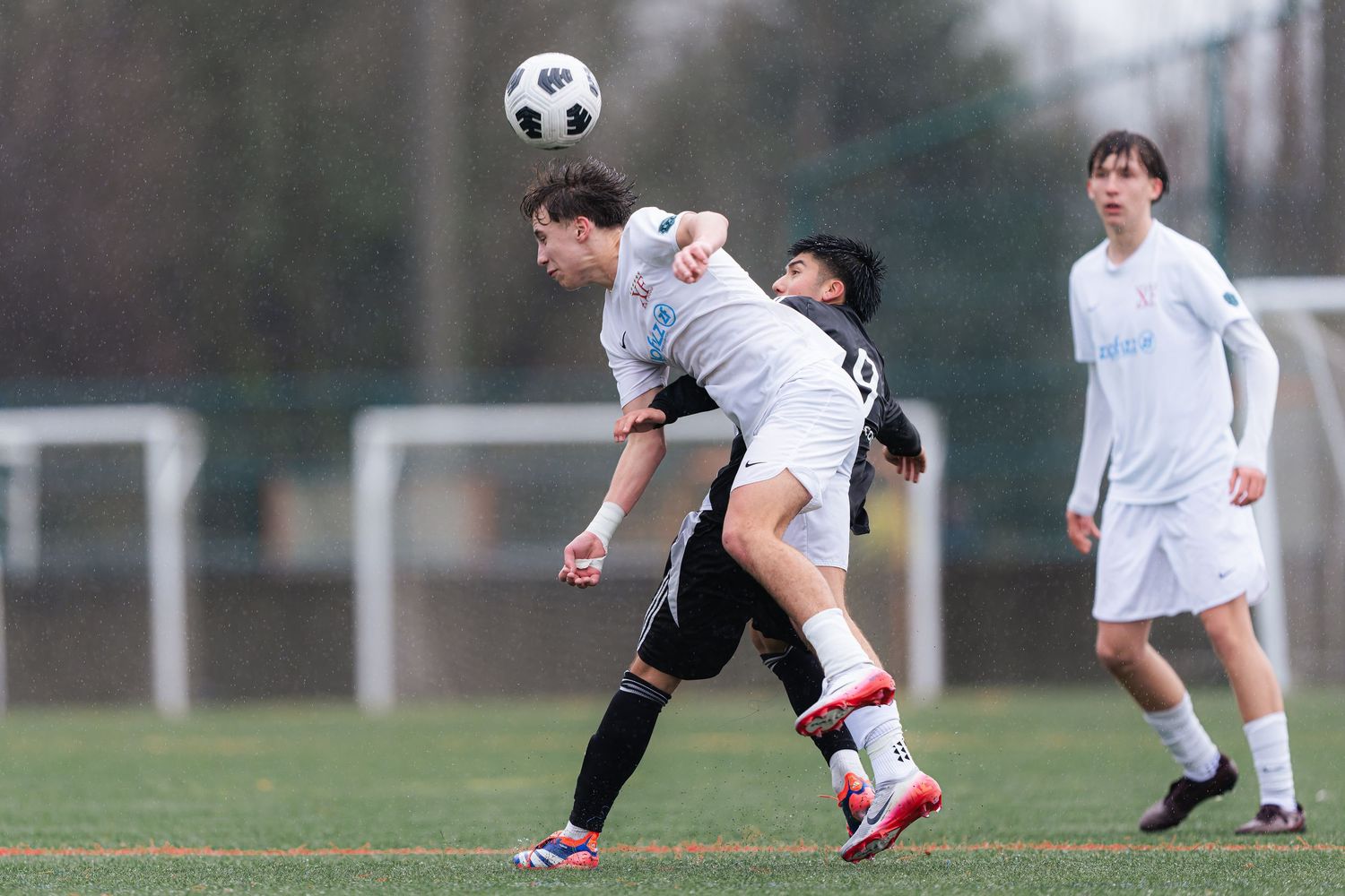 Soccer players compete for possession of the ball during an intense match on a grass field.