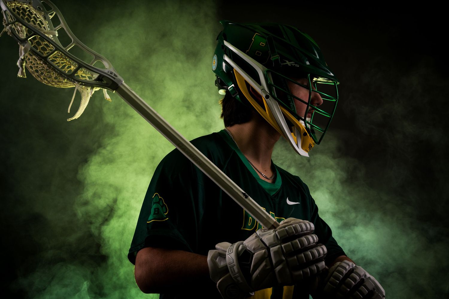 Baseball player in dark uniform swings bat against dramatic green smoke background during professional game.