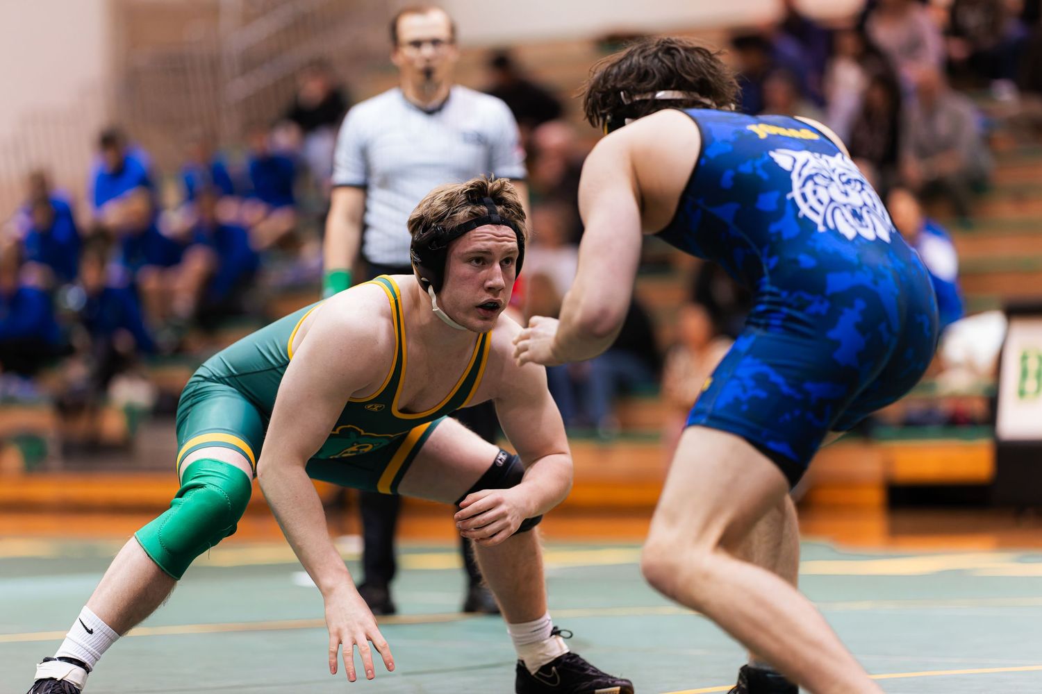 Two wrestlers grapple on a mat during an intense wrestling match competition.
