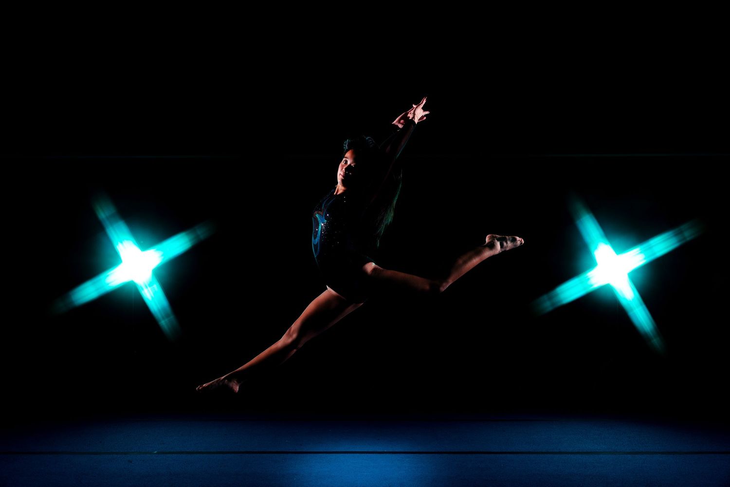 Glowing blue star-shaped lights shine against a dark background in a dramatic performance display.