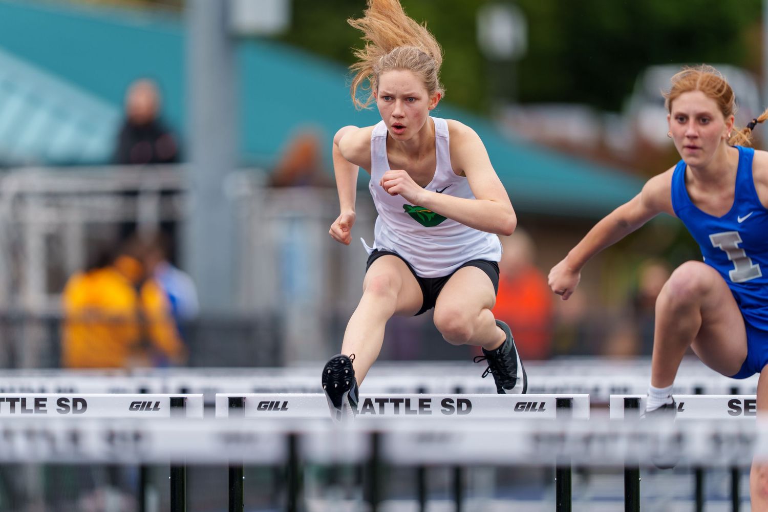 Athletes leap over hurdles during an outdoor track and field competition event.