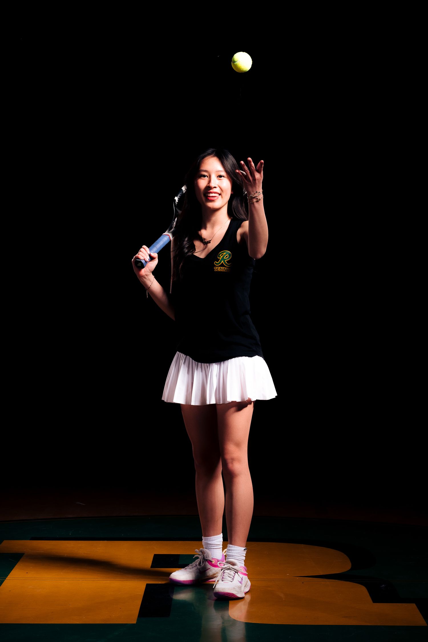 Tennis player in dark outfit serves ball against black background in dramatic lighting sequence.