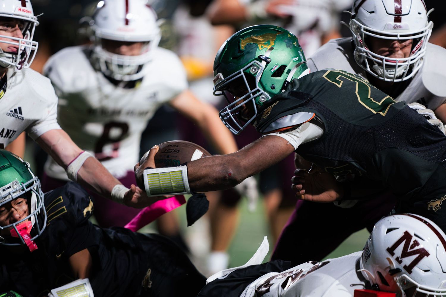 Football players in green and white uniforms engaged in intense gameplay action.