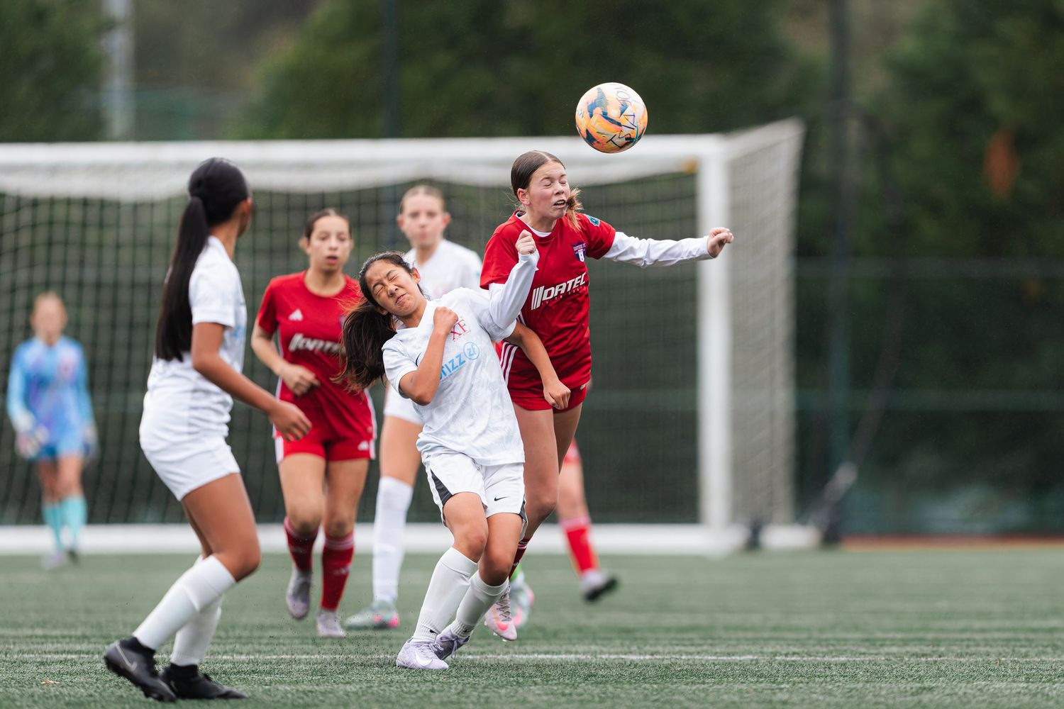 Soccer players compete for possession of the ball during an intense match on an outdoor field.