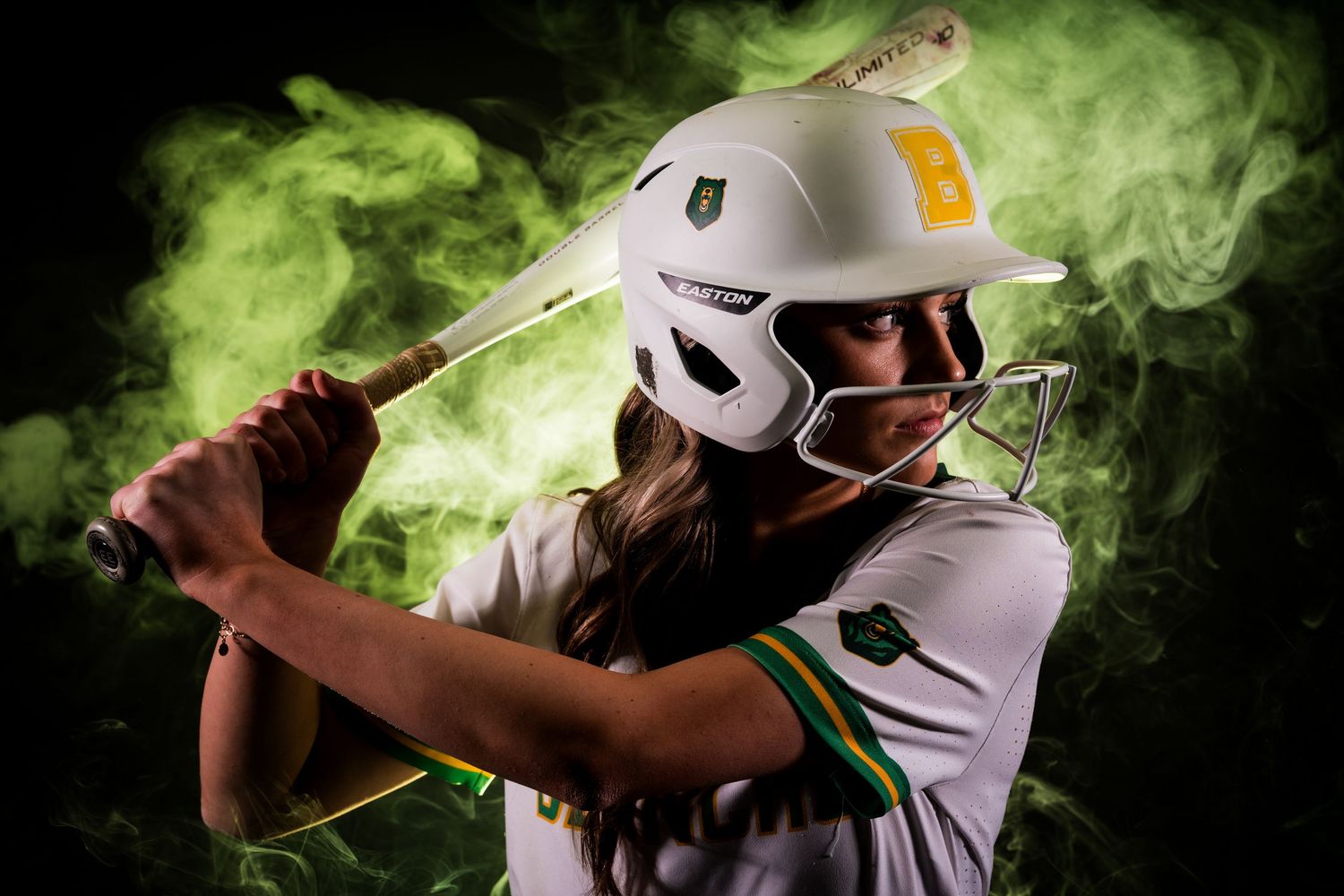 Baseball player in white uniform swings bat surrounded by dramatic green smoke effect during action shot.