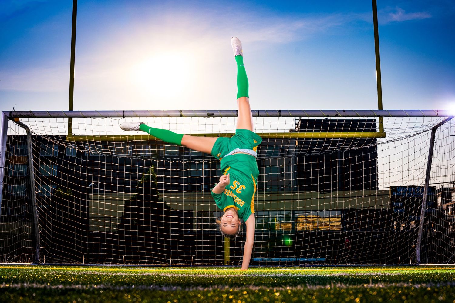 Soccer goal net silhouetted against bright blue sky with green flag.