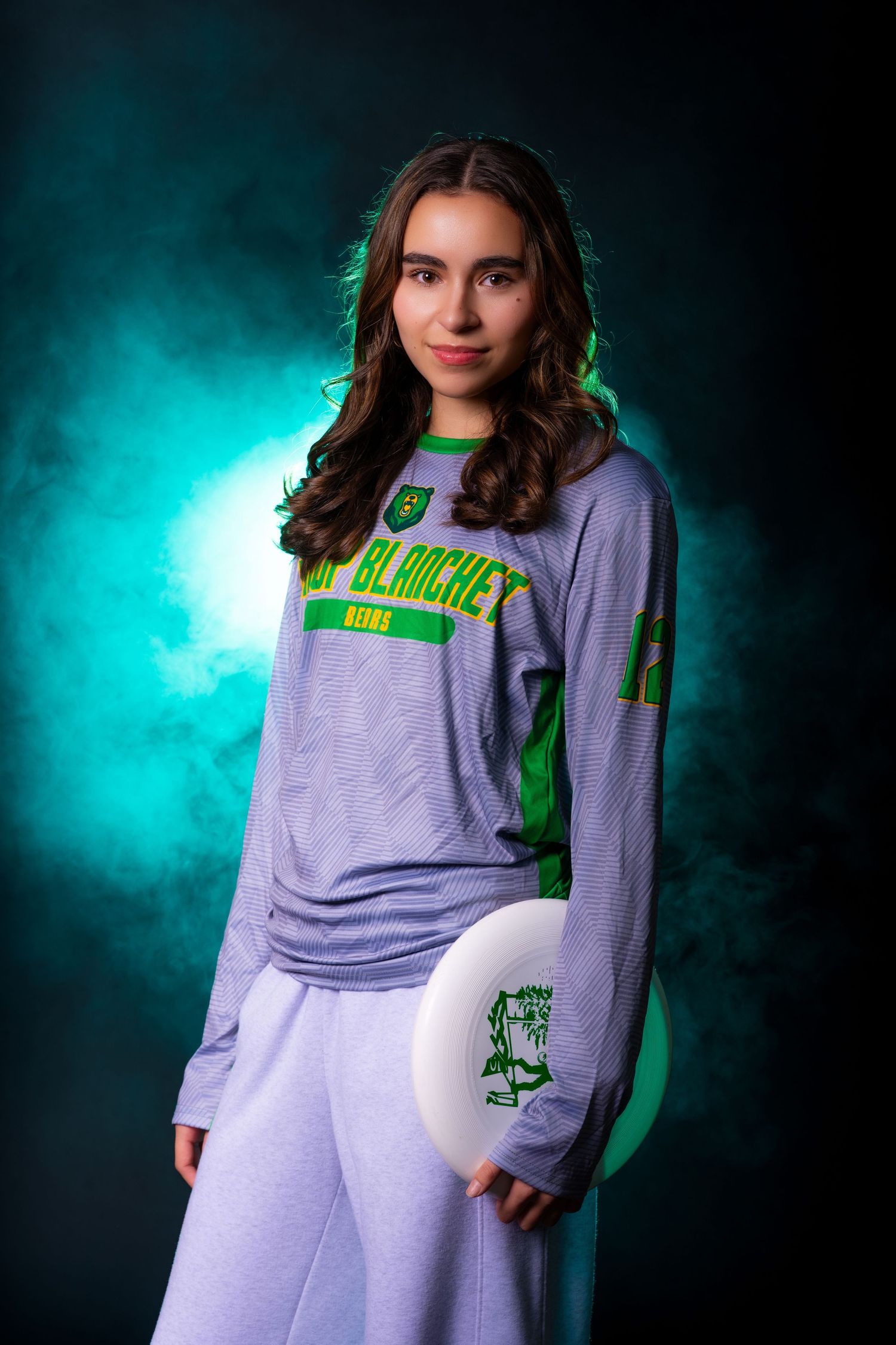 Model wearing a light gray casual sweatsuit with neon green accents against a turquoise smoky background.