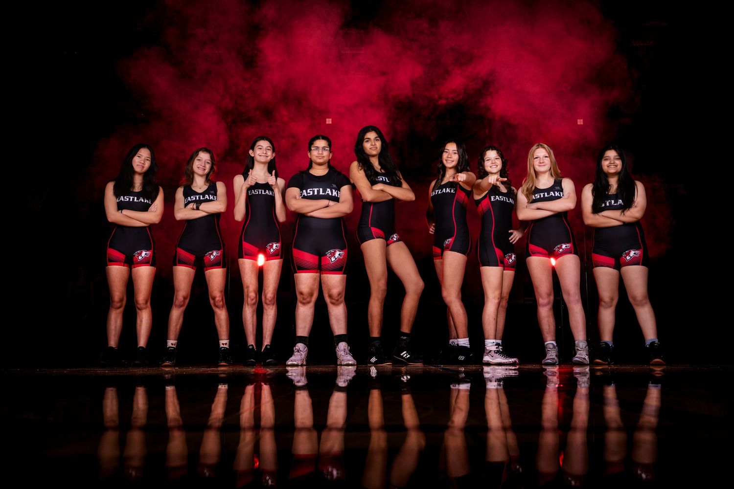 A row of volleyball players stand together in their uniforms against a dark background.