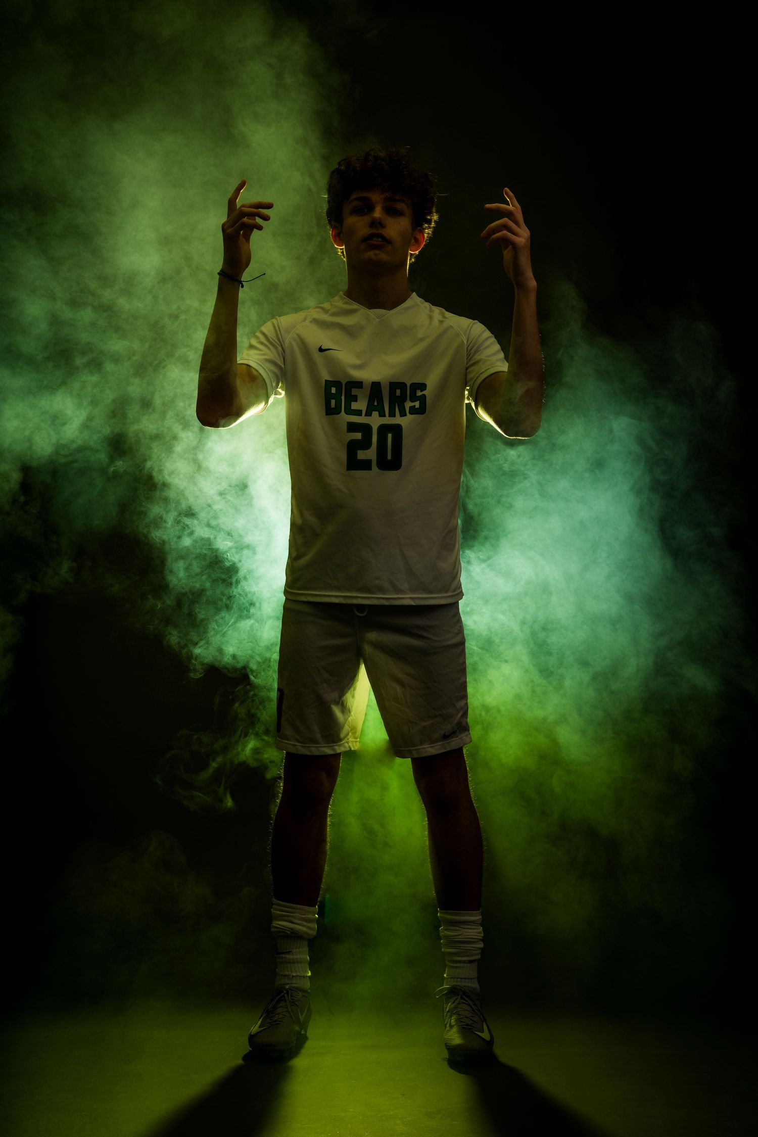 Basketball player in white Bears jersey poses dramatically in green smoke effects on dark background.