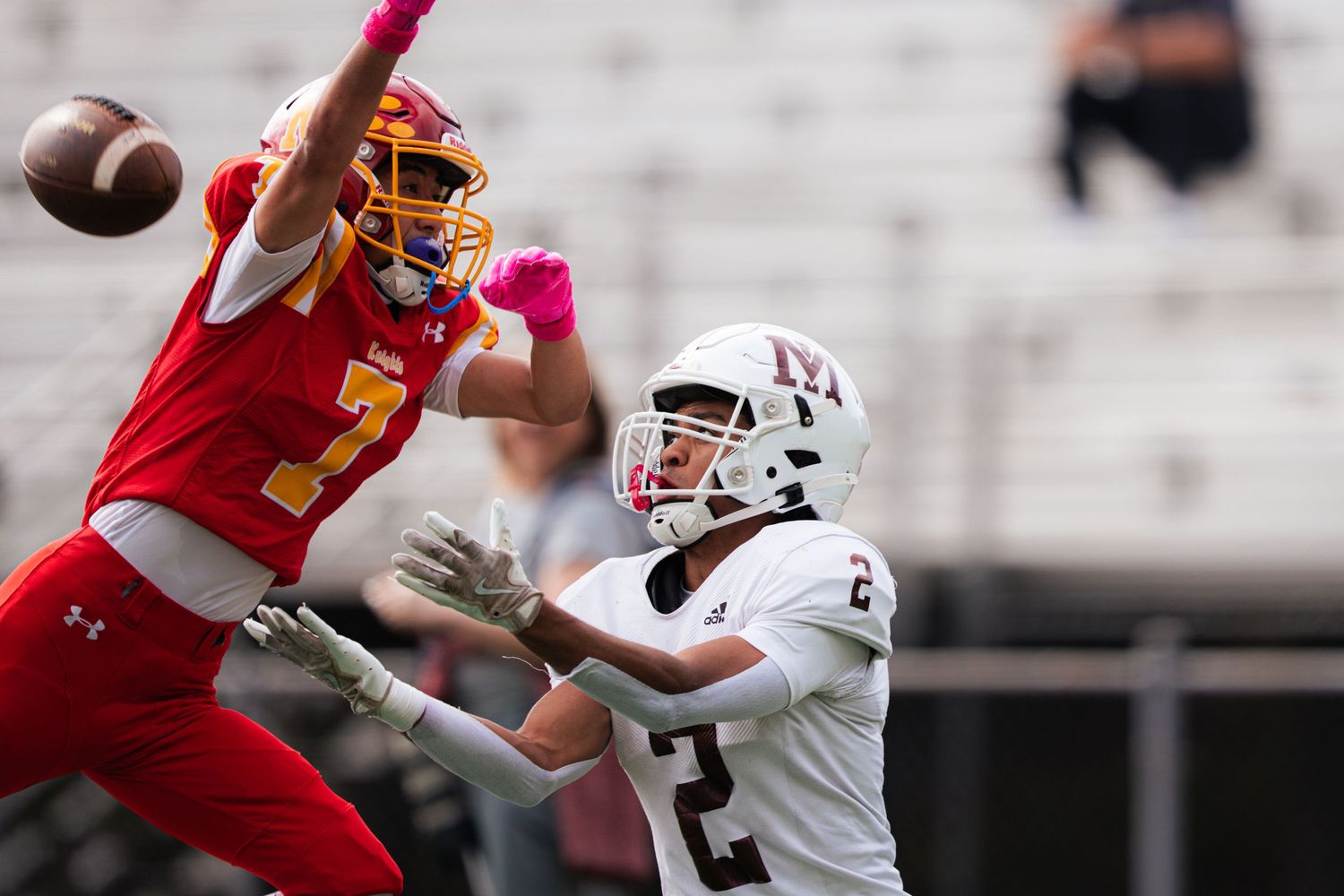 Football players from opposing teams compete for a pass during an intense game moment.