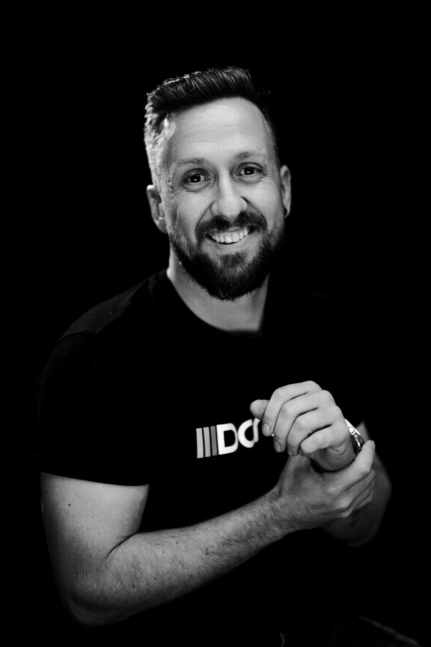 A series of black and white portraits showing someone smiling and gesturing while wearing a dark shirt against a dark background.