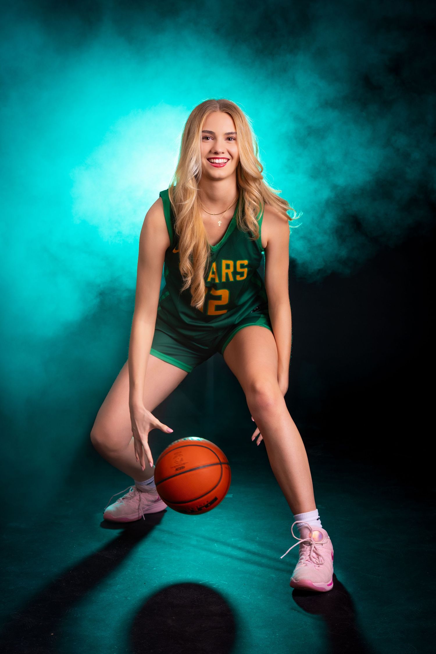 Basketball player in green Bears jersey crouches with orange ball against teal backdrop.