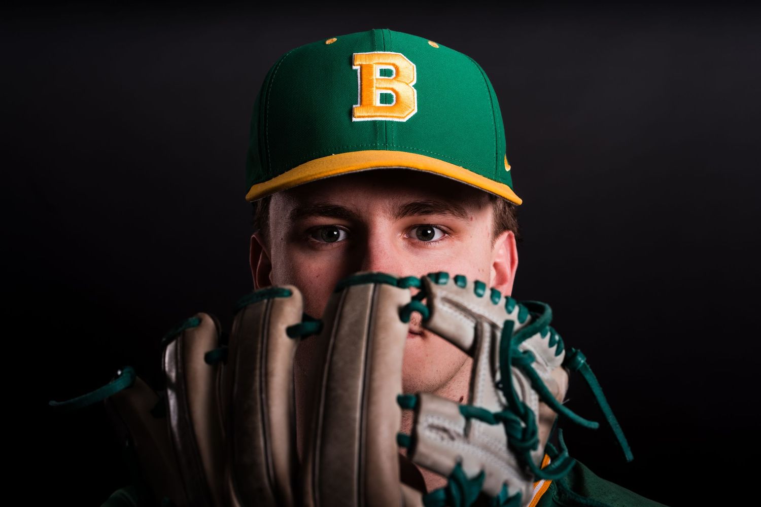 Baseball equipment including cap and glove photographed against dark background with dramatic lighting.