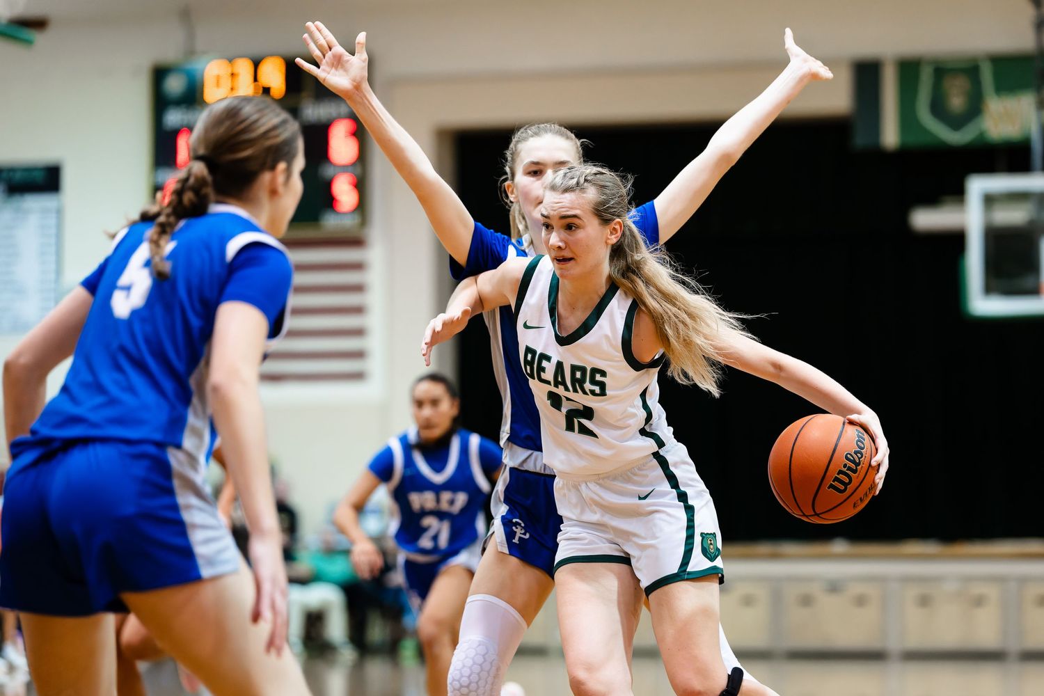 Basketball player in white jersey dribbles while being defended during intense game action.