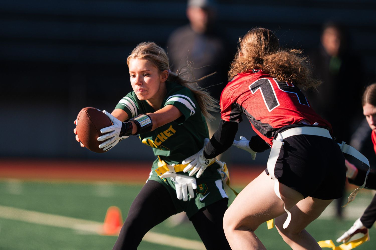 Flag football players compete intensely during a match as one player attempts to dodge a defensive move.
