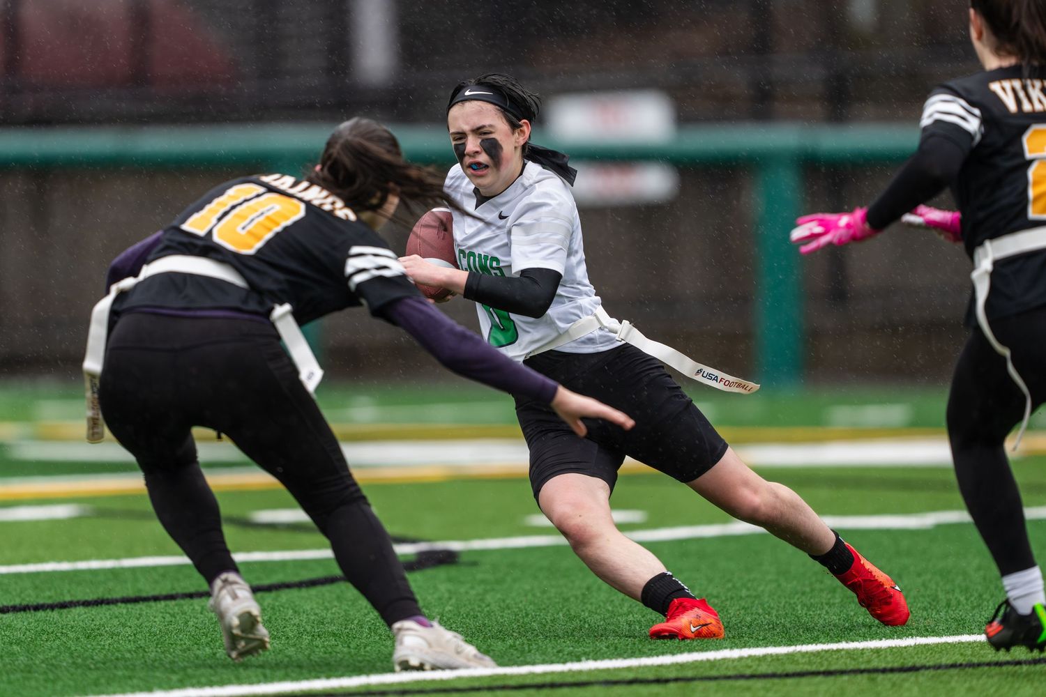 Rugby players dive and tackle during an intense match on a green sports field.