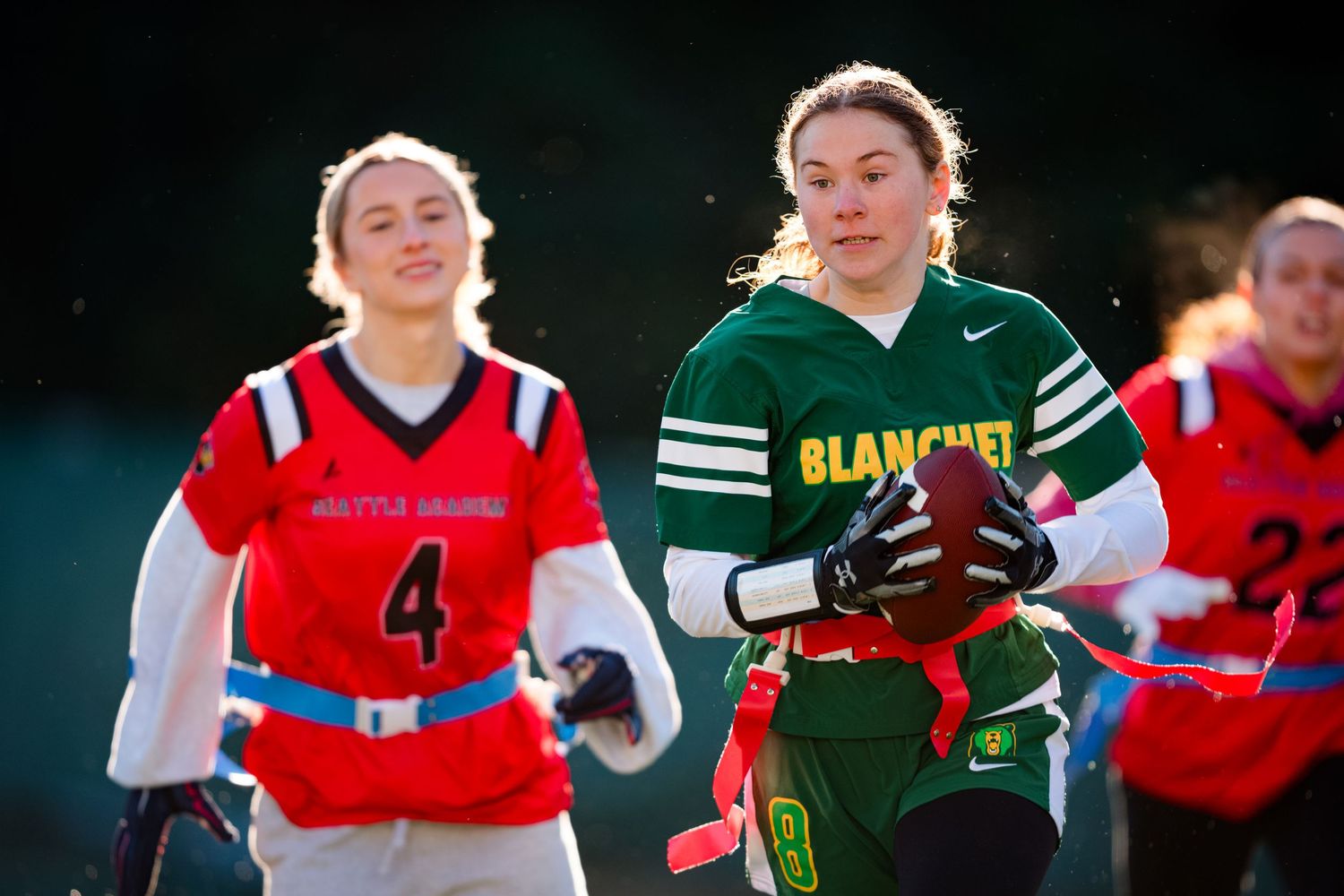 A group of softball players in red and green uniforms celebrate during a game on the field.