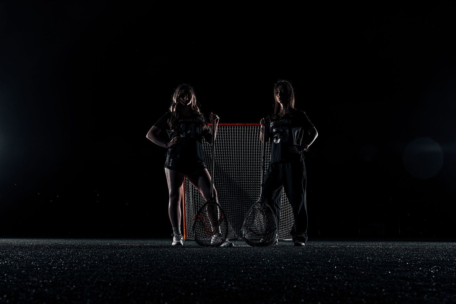 A dark silhouette of people standing in a dimly lit space with dramatic lighting and shadows.