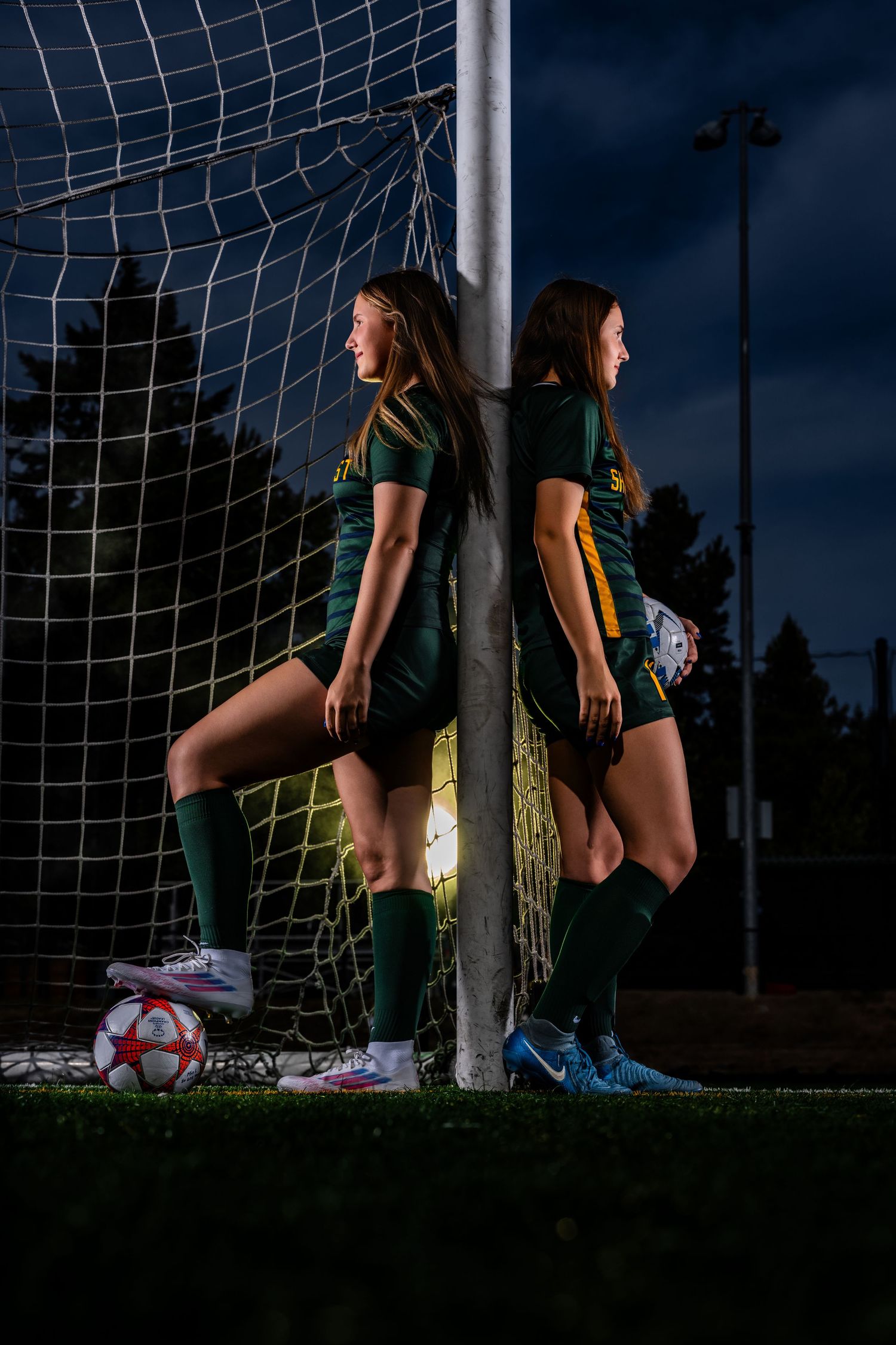 Dramatic nighttime soccer scene with player and goal post against dark sky.