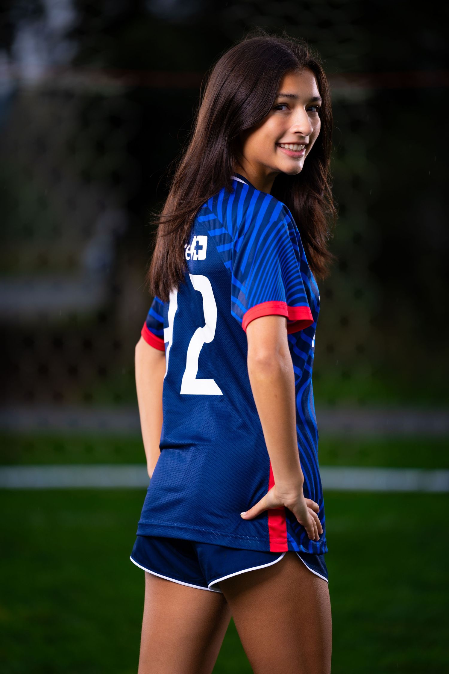 Athletic woman in navy blue sports jersey and shorts poses outdoors in a series of dynamic shots.