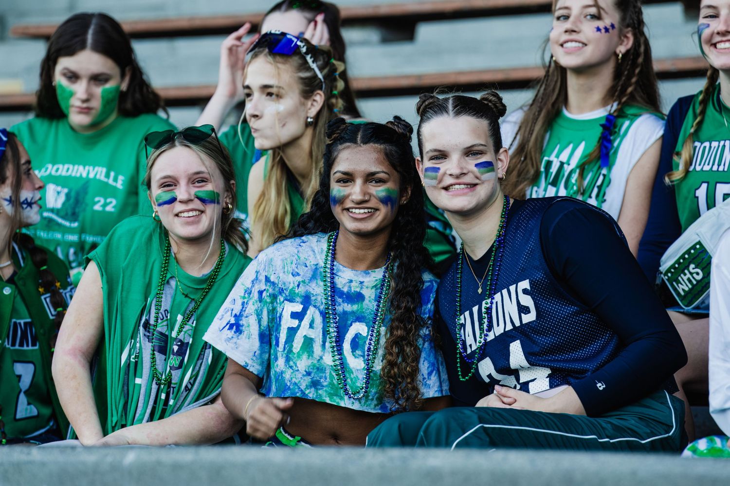 Excited fans in green jerseys cheer enthusiastically from stadium bleachers during a sporting event.