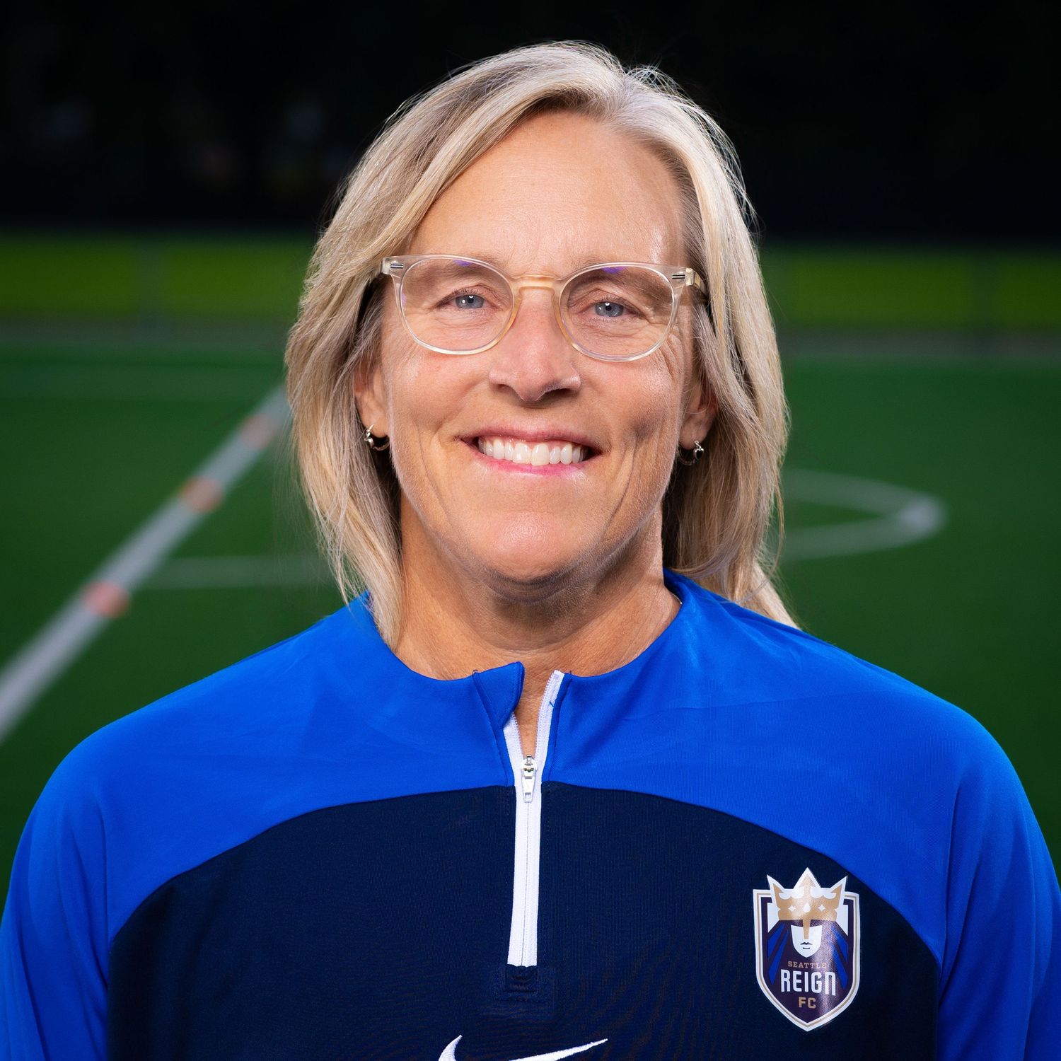 Person in blue Nike quarter-zip athletic jacket smiling at camera.