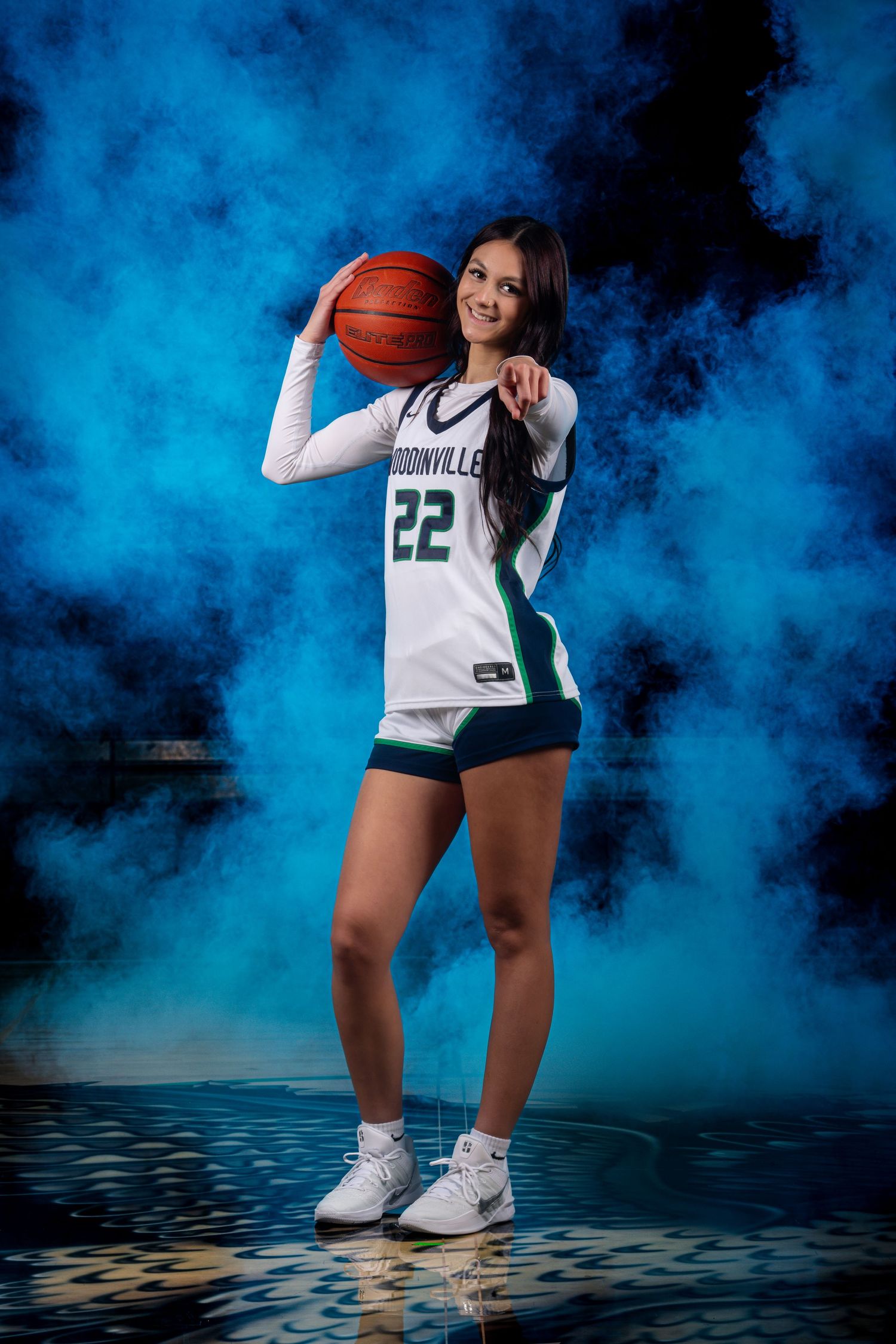 Basketball player in white jersey number 22 demonstrating dribbling skills against blue backdrop.