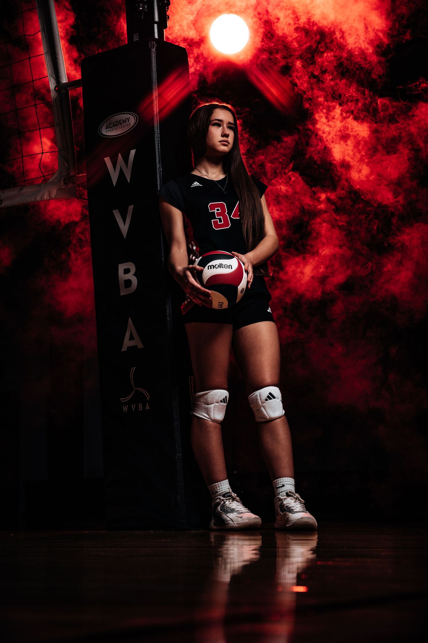 Volleyball player in black uniform poses against dramatic red smoke effect background in sports photography series.
