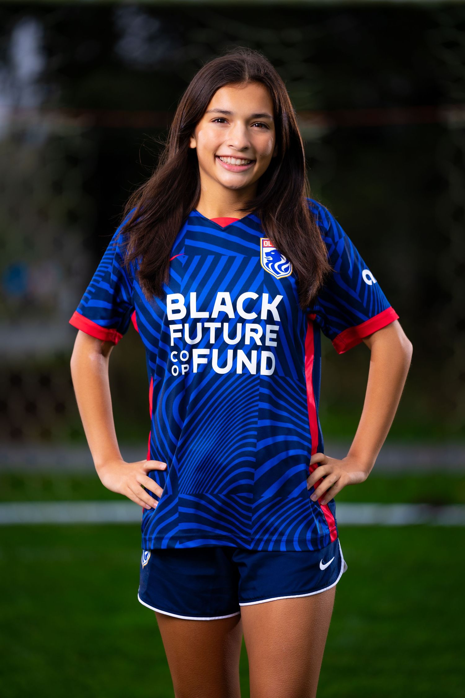Woman wearing blue and red sports jersey with 'Black Future Fund' text stands in outdoor setting.