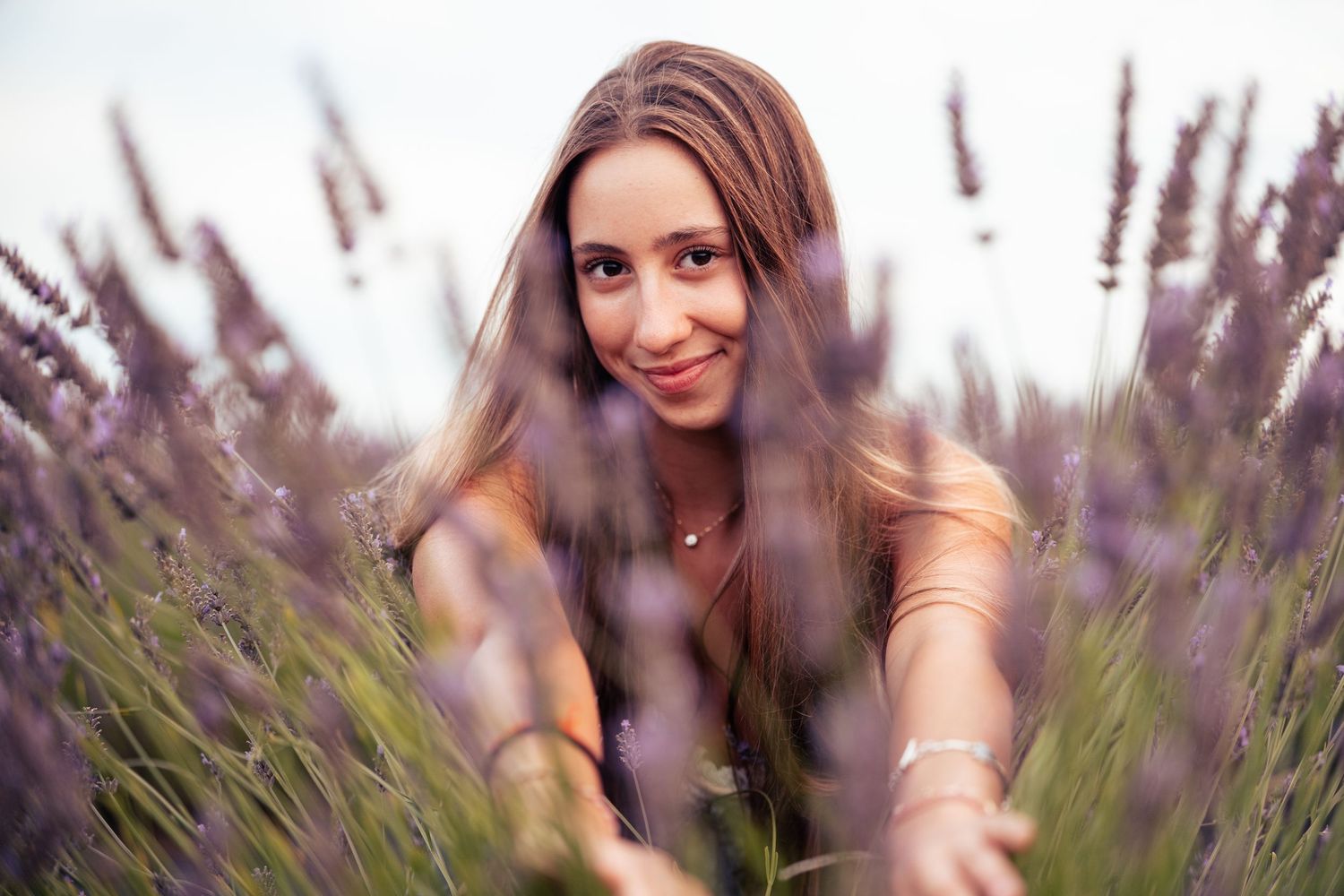 A high school senior poses playfully in a blooming lavender field during golden hour photographed by Carlos Sanchez Photography in Seattle